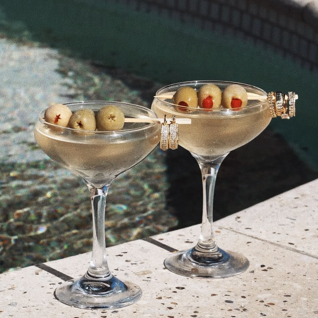 Jewelry resting on cocktail glasses beside the pool